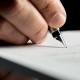 Macro shot of a hand of a businessman signing or writing a docum